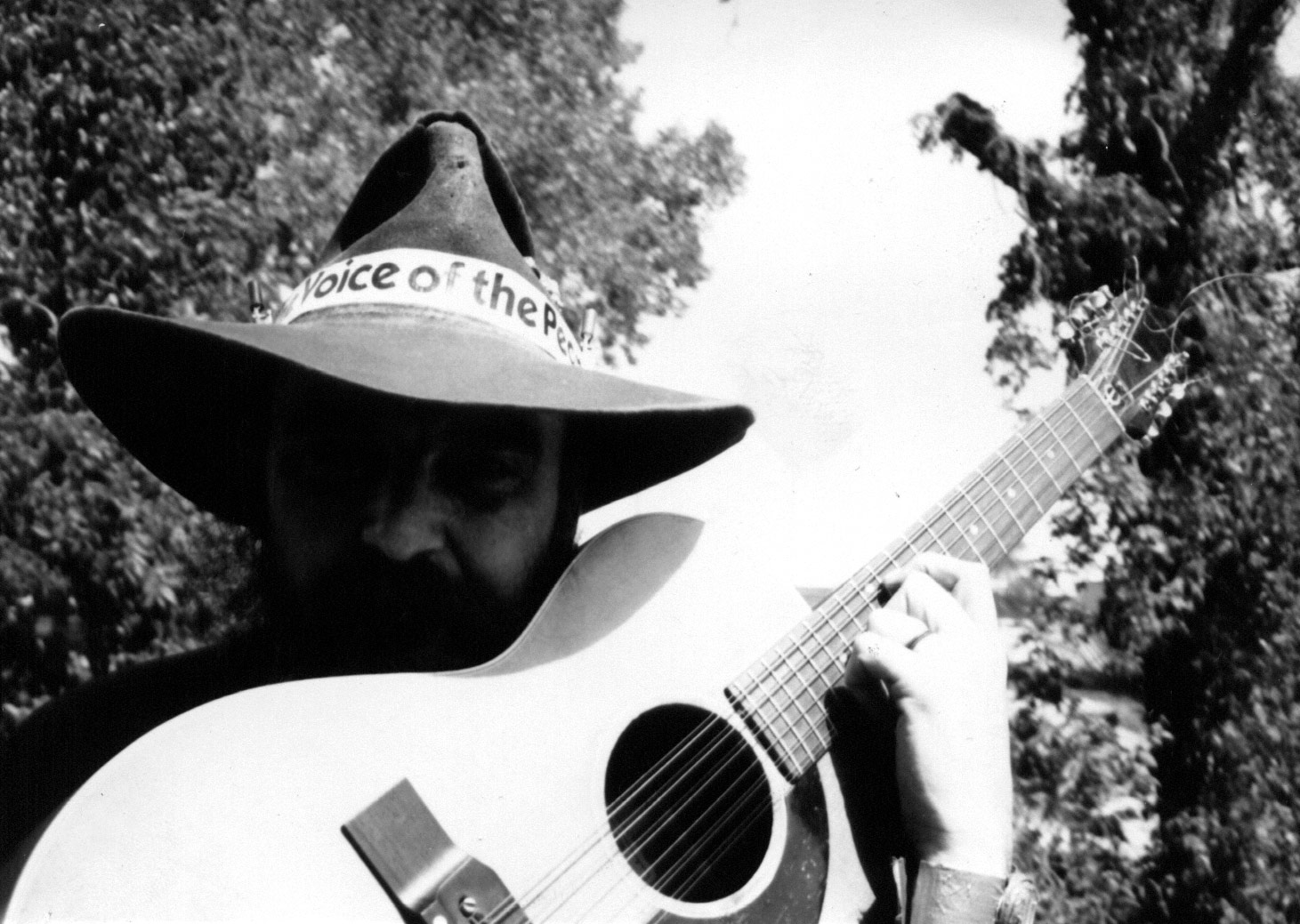 Blaze in cowboy hat, "Voice of the People" hatband, holding a twelve string guitar